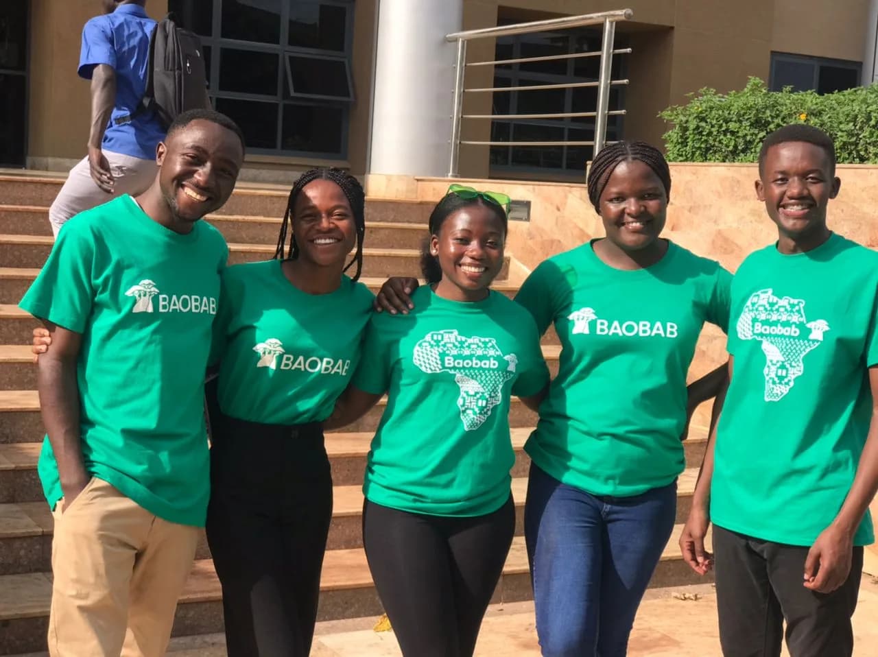 Eric and fellow Baobab community members wearing green Baobab shirts outdoors