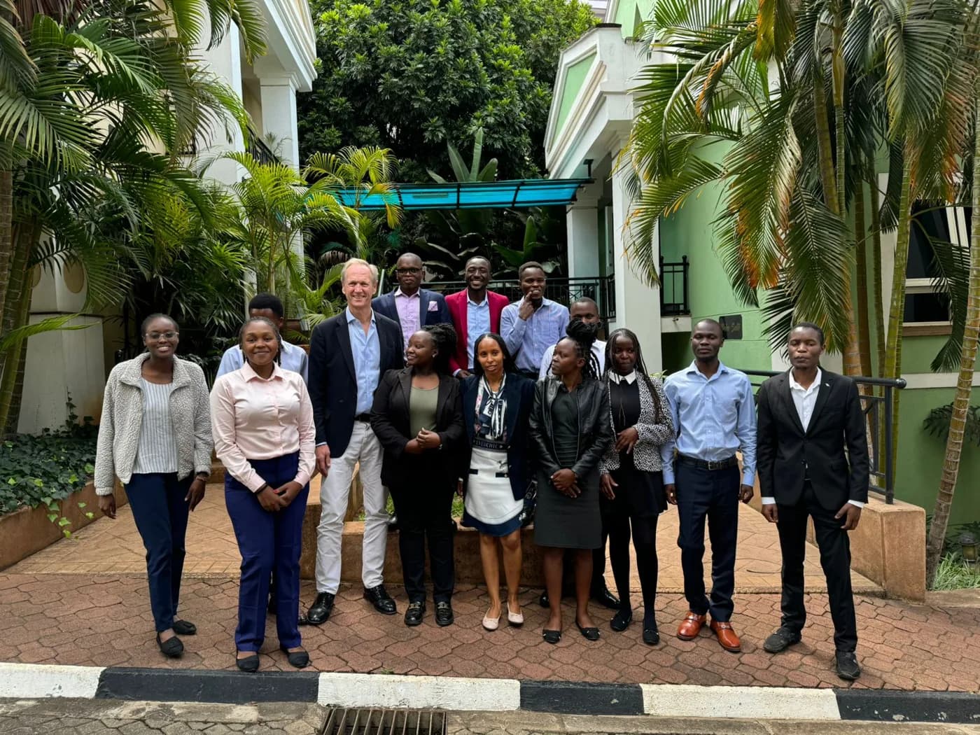 A group of participants gathered for a photograph in a leafy courtyard