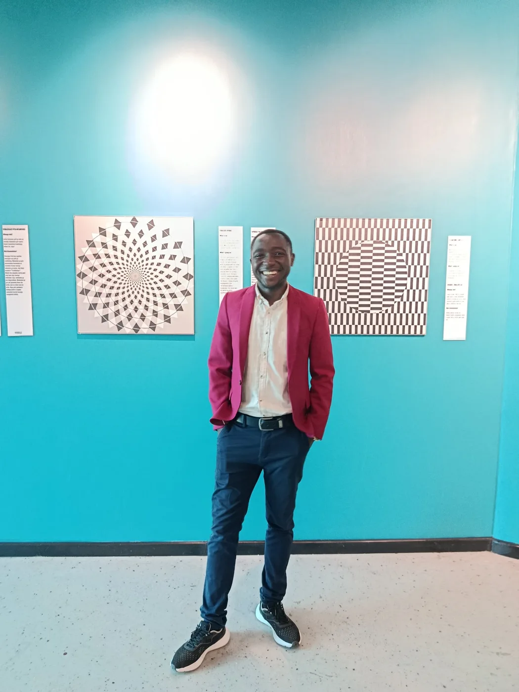 Eric in a red jacket beside a colourful exhibition wall
